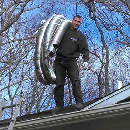 Chimney technician standing on roof carrying new chimney liner