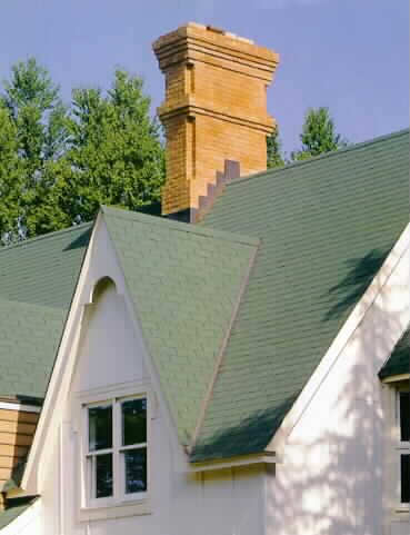 Close up of white house with green roof and beige brick chimney